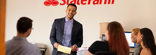Un orador, parado en frente de un logotipo de State Farm, se dirige a sus compañeros de trabajo.